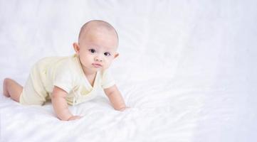 glückliche familie, süßes asiatisches neugeborenes baby, das auf einem weißen bett liegt, blick in die kamera mit einem lachenden lächeln, einem glücklichen gesicht. kleines unschuldiges neugeborenes entzückendes kind am ersten lebenstag. Muttertagskonzept. foto