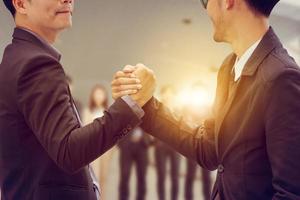 Geschäftsmann-Handshake über verschwommenem Teamwork-Hintergrund von Geschäftsleuten, erfolgreiches Partnerschaftskonzept. foto