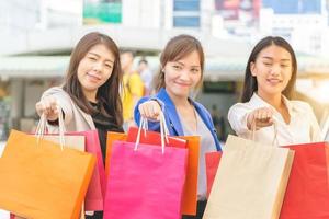 viel Spaß beim Einkaufen drei schöne junge Freundinnen mit Taschen auf der Straße. gruppe kaukasischer frauen, die in der stadt einkaufen foto