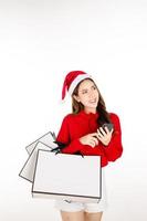 eine süße asiatische frau, die ein rotes kleid mit einer weihnachtsmütze trägt, hält eine geschenkbox. Einkaufskonzept. foto