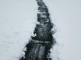 Asphaltauffahrt mit weißem Schneeschaufeln im Winter foto