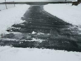 Asphaltauffahrt mit weißem Schneeschaufeln im Winter foto