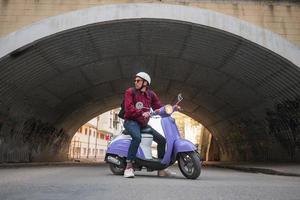 junger stylischer Mann mit buntem Motorroller foto