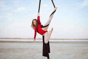 Übungen mit Luftseide im Freien, Himmelshintergrund. schöne fitte frau, die akrobatik in der luft trainiert. foto