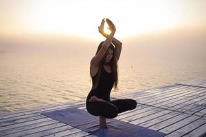 junge frau, die in yoga-asans, morgenseehintergrund aufwirft foto