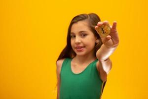 Kind, das Kryptowährung in Metall hält. Goldmünze. golden. auf gelbem Hintergrund. foto