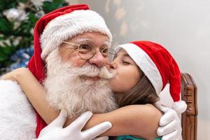 weihnachtsmann liefert einem kleinen mädchen eine geschenkbox. Heiligabend, Lieferung von Geschenken. foto