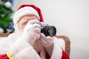 weihnachtsmann, der vintage-kamera hält. Porträt isoliert auf gelbem Hintergrund. foto