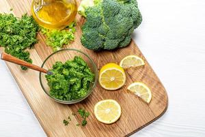 Hintergrund für gesunde Ernährung. mit frischen Kräutern und Gemüse auf dem Küchenbrett mit Zitronenscheiben und Olivenöl pürieren foto