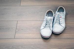 Sport weiße Turnschuhe, Converse, Schuhe zum Gehen, Gehen, auf einem braunen Holzboden. Anti-Corn-Sticker auf der Rückseite der Ferse. Platz für Texte. foto