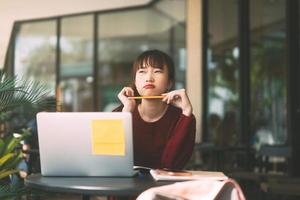 junge erwachsene asiatische College-Studentin mit Laptop zum Lernen im Café am Wintertag. foto