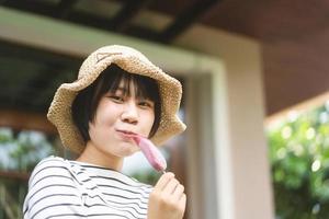 asiatische Teenager-Frau im Sommer entspannen Sie sich beim Essen von Eis zu Hause im Garten im Freien. foto