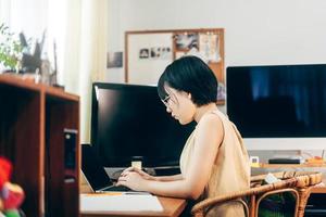 junge erwachsene asiatische frau bleibt und arbeitet von zu hause aus mit laptop für internet online. foto