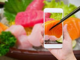 weibliche hand, die foto des sashimi-sushi-sets macht