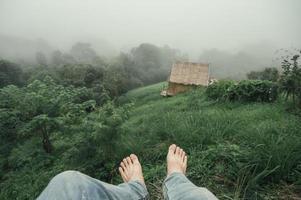 barfüßiger Mann mit Jeans, der im Nebel im Regenwald am Berg hängt foto