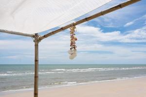 Muschel-Souvenir-Hängedekoration auf Pavillon mit tropischem Strand foto