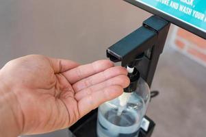 Alkoholgel auf der Handfläche von einer berührungslosen Maschine, um die Ausbreitung von Infektionen zu verhindern foto