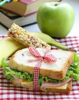 Sandwich mit Schinken, Apfel, Banane und Müsliriegel foto
