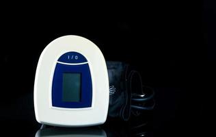 blau-weißes digitales Blutdruckmessgerät mit Manschette mit großem Bereich isoliert auf dunklem Hintergrund. Gesundheitscheck-Konzept foto