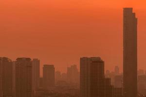 Luftverschmutzung. smog und feinstaub der pm2.5 bedeckten stadt morgens mit rotem sonnenaufgangshimmel. stadtbild mit verschmutzter luft. schmutzige Umgebung. städtischer giftiger Staub. ungesunde Luft. städtisches ungesundes Leben. foto