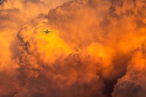 Flugzeug fliegt über dramatischen orangefarbenen Himmel und Wolken abstrakten Hintergrund. Draufsicht auf orangefarbene Wolken. Kunstbild der orangefarbenen Wolkenstruktur. lange Reise mit einer kommerziellen Fluggesellschaft. erstaunlicher Flug bei Sonnenuntergang. foto