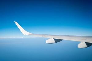 Flügel des Flugzeugs über weißen Wolken. Flugzeug fliegt am blauen Himmel. malerische Aussicht aus dem Flugzeugfenster. Flug einer kommerziellen Fluggesellschaft. Flugzeugflügel über Wolken. Konzept der Flugmechanik. internationaler Flug. foto