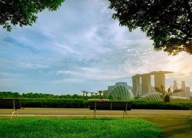 Landschaft von Hotel- und Geschäftsgebäuden. leere Holzbank im öffentlichen Park von Singapur. stadtbild von singapur moderne und finanzstadt in asien. marina bay wahrzeichen von singapur. Fahrrad fahrendes Kind foto
