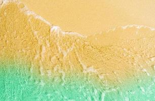 Blick von oben auf den goldenen Sandstrand am Meer mit smaragdgrünem Meerwasser. sommerferien auf tropischem paradiesstrandkonzept. Wasserspritzer am Sandstrand. sommergefühl. foto