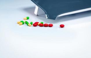 rote tabletten und grün-gelbe kapselpillen mit medikamententablett auf weißem tisch. Pharmaindustrie. Vitamine und Nahrungsergänzungsmittel. Pharmazeutisches Konzept. apotheke produkte. Gesundheit und Medikamente. foto