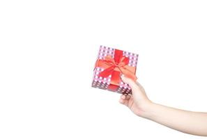 Nahaufnahme schöne und gesunde Frauenhände mit gepflegter Maniküre halten eine Weihnachtsgeschenkbox, die mit einem roten Band isoliert auf weißem Hintergrund umwickelt ist foto