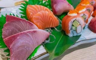 japanisches lebensmittelset serviert auf weißem teller. Lachs-Sushi und Sashimi am Tisch im Restaurant. frisches rohes Fischfleisch in Scheiben geschnitten und Reisrollen mit japanischem Essig mit Meeresfrüchten und Gemüse. Gesundes japanisches Essen. foto