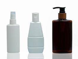 drei weiße und braune kosmetische Plastikflaschen mit unterschiedlicher Art von Kappenpumpe, Spray und Kappe isoliert auf weißem Hintergrund mit leerem Etikett und Kopierraum foto