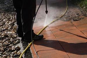 Mann, der die Terrasse mit Hochdruckwasser reinigt. foto