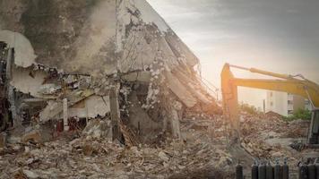 zerstörte Bauindustrie. Gebäudeabriss durch Explosion. Verlassenes Betongebäude mit Schutt und Schrott. gelber bagger, der in der vernichtungsstätte arbeitet. foto