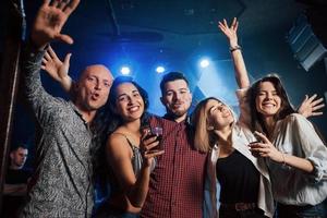 tanzen, trinken und Spaß haben. Schöne Jugendliche feiern zusammen mit Alkohol im Nachtclub foto