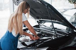 Problem wird gelöst. auf den schönen Job. autosüchtige frau repariert drinnen schwarzes auto foto