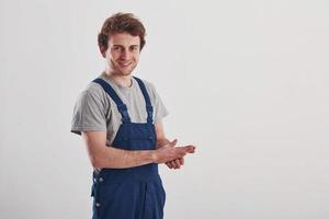 machen Sie sich bereit für die Arbeit. Mann in blauer Uniform steht vor weißem Hintergrund im Studio foto