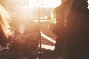 Sonnenschein im Herbsttag. Eine Gruppe von Freunden beschließt, das Wochenende mit Gitarre und Alkohol auf dem Dach zu verbringen foto