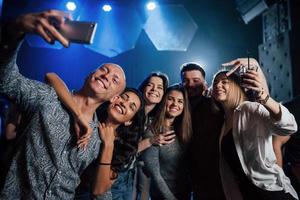moderne Fotomode. freunde, die selfie im schönen nachtclub machen. mit Getränken in den Händen foto