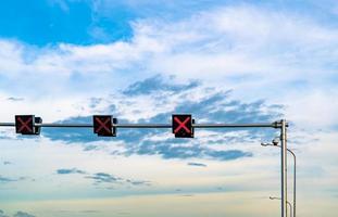 Ampel mit roter Farbe des Kreuzzeichens auf blauem Himmel und weißem Wolkenhintergrund. falsches Vorzeichen. Kein Einfahrt-Verkehrszeichen. rotes kreuz führung stop go ampel. warnende Ampel. foto