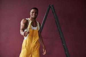 Mann mit starken Händen. junge afroamerikanische arbeiter in der gelben uniform haben einen job foto