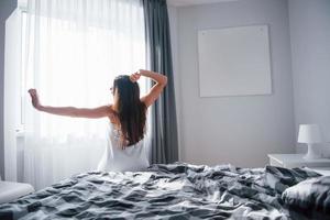 großes rotes Herz an der Wand. hübsche junge frau, die morgens in ihrem zimmer auf dem bett sitzt foto