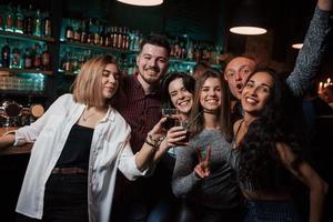 Freude und Zufriedenheit. Schöne Jugendliche feiern zusammen mit Alkohol im Nachtclub foto