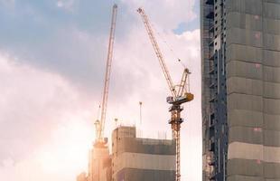 Baustelle mit Kran und Gebäude. Immobilienwirtschaft. kran verwenden rollenhebegeräte auf der baustelle. Baustelle Mehrfamilienhaus. baukranarbeiten gegen den himmel. foto