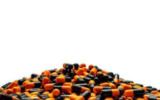 Closeup Haufen von orange-schwarzen Kapselpillen auf weißem Hintergrund. Vitamine und Nahrungsergänzungsmittel. Pharmaindustrie. globales gesundheitskonzept. Herstellung von Kapselpillen. Drogenüberkonsum im Gesundheitssystem. foto