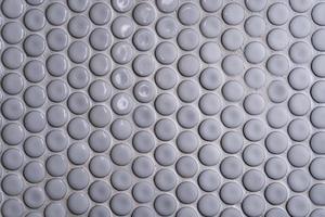 weiße keramikfliesenwand mit vielen kleinen runden einzigartigen mustern. Die Draufsicht auf die Badezimmerwandfliese ist eine runde Knopffliese. Kreis weiße Mosaikfliese abstrakte Textur Hintergrund. foto