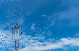 Hochspannungsmast und Übertragungsleitungen. Strommast mit blauem Himmel und weißen Wolken. Kraft und Energieeinsparung. Hochspannungsnetzturm mit Drahtkabel an der Verteilerstation. foto