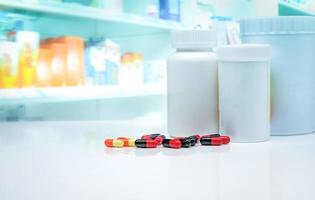 Kapselpillen mit Medikamentenflaschen auf weißem Tresen auf verschwommenem Medikamentenregal in der Apotheke. Hintergrund der Apotheke. Pharmaindustrie. gesundheitswesen und medizinkonzept. verschreibungspflichtige Medikamente. foto