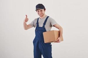 Konzeption des Postdienstes. Kerl mit Kiste in den Händen steht vor weißem Hintergrund im Studio foto