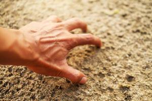 männliche Hand, die etwas im Sand berührt foto